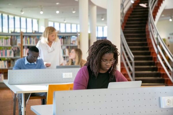 Diverse group of students studying in a modern university library with focus on diligent learning.